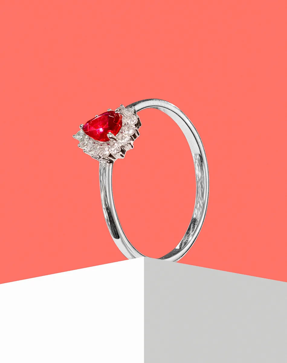 Silver ring with a red gemstone and diamonds.