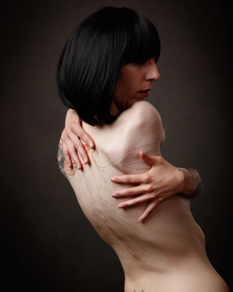 Person with tattoos poses with arms crossed.