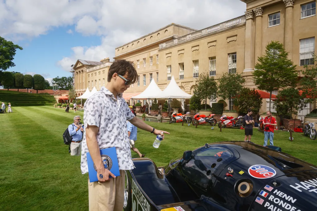 Person inspecting racing car outside historic building