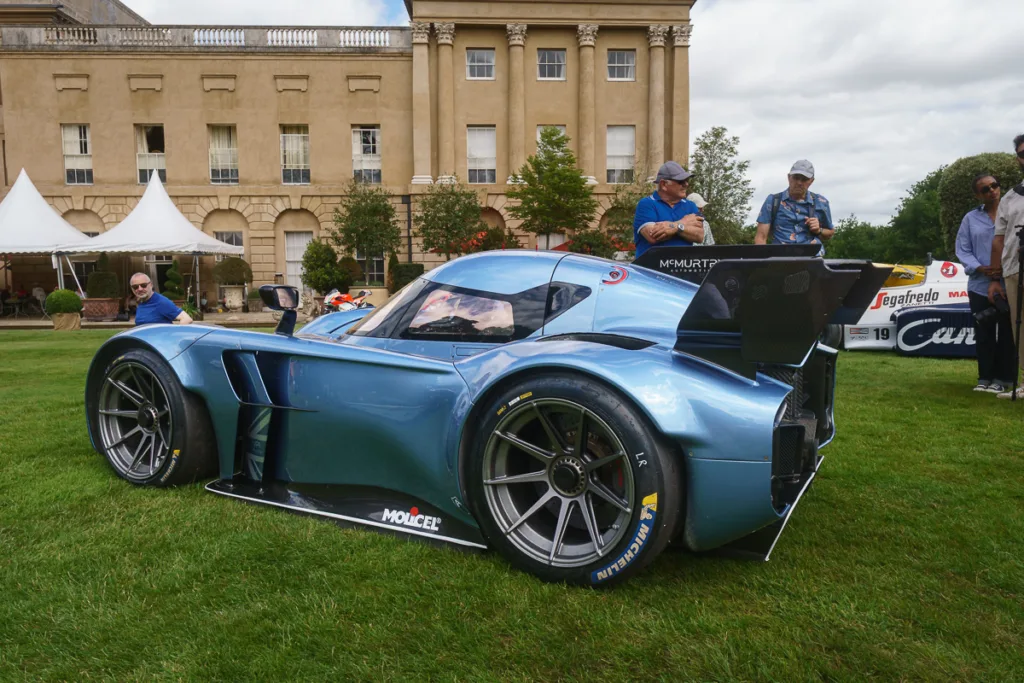 Blue race car displayed at event with people observing.