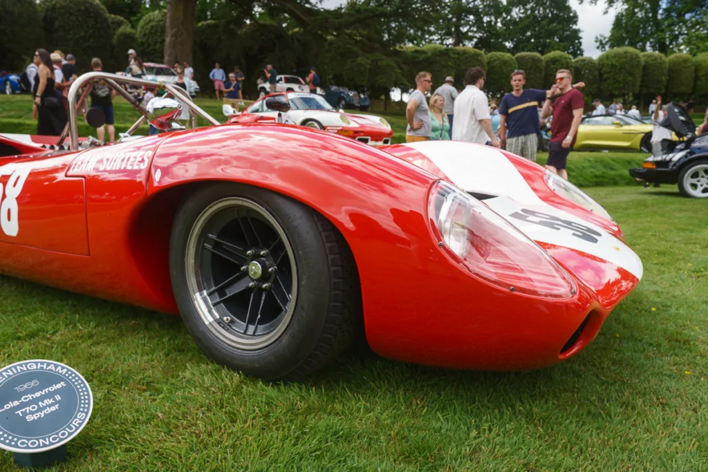 Classic red race car at outdoor car show.