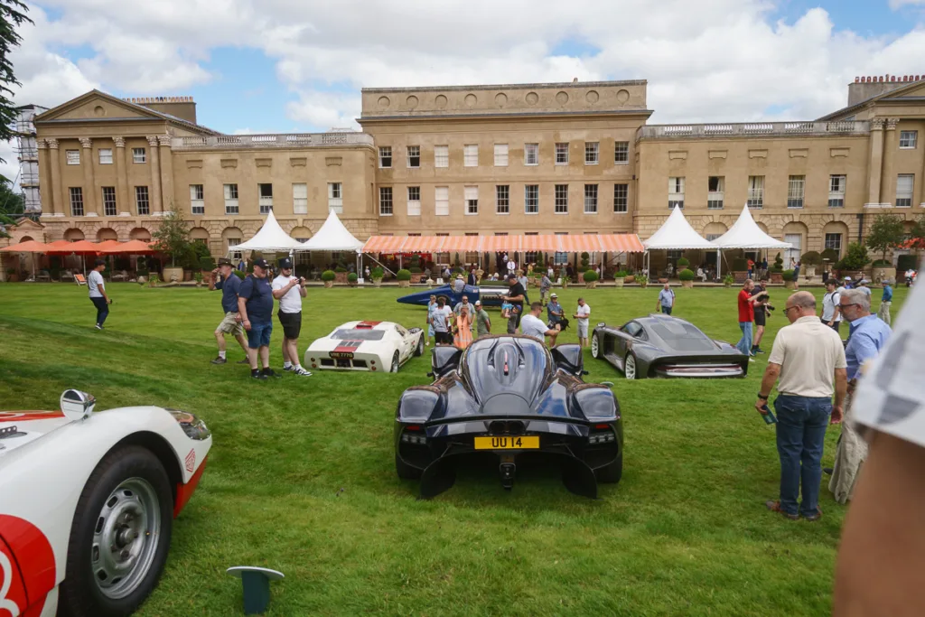 People enjoying car show at historic mansion event.
