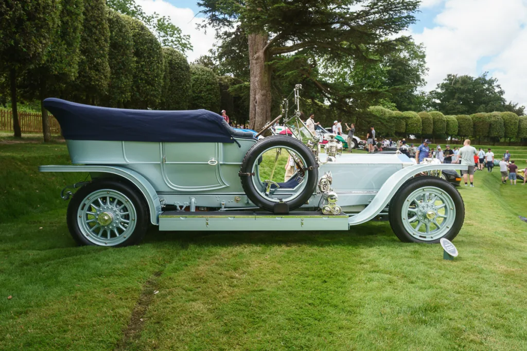 Vintage car displayed on green lawn at event.
