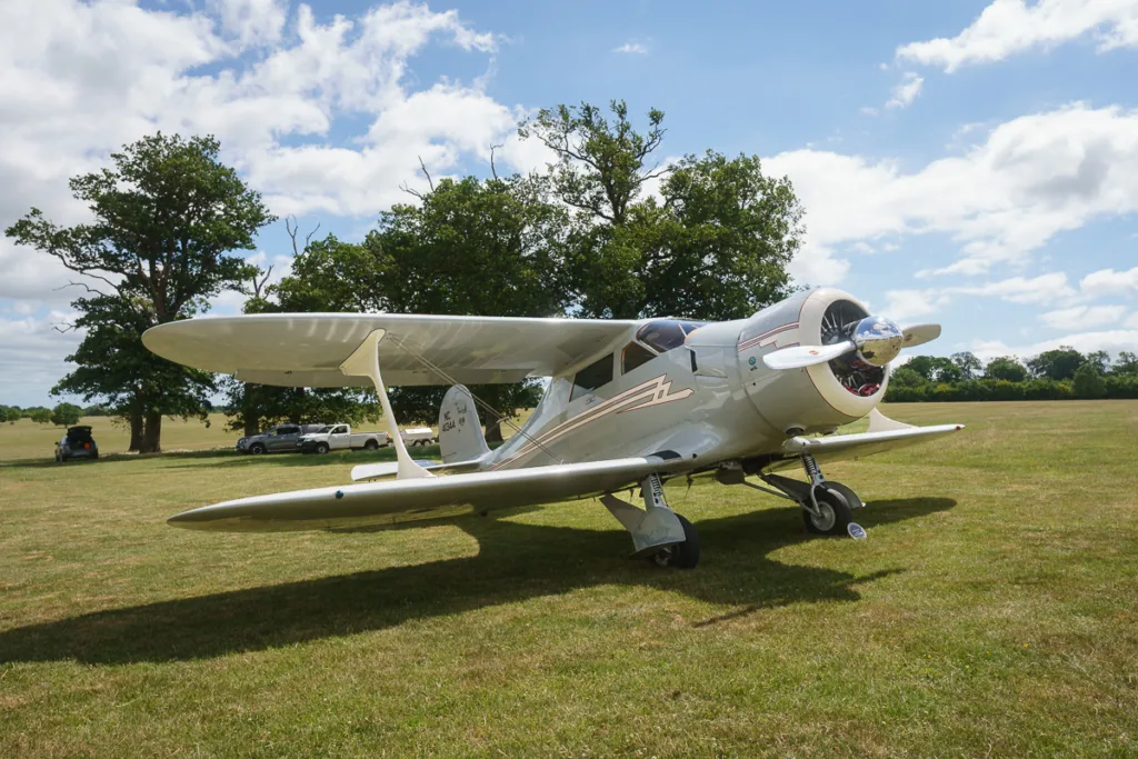 Vintage plane on grassy field, sunny day.