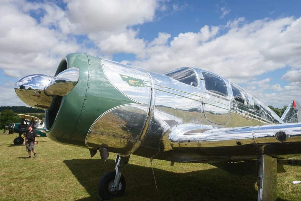 Shiny vintage aircraft on grassy field during show.