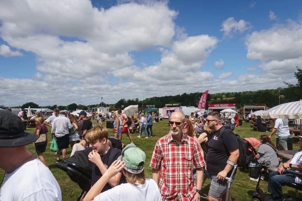 People enjoying a sunny outdoor food festival.