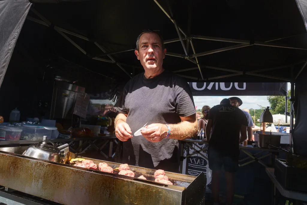 Man cooking meatballs at outdoor food stall.