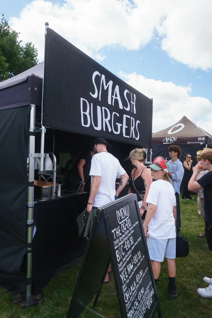 People queue at Smash Burgers food stall outdoors.