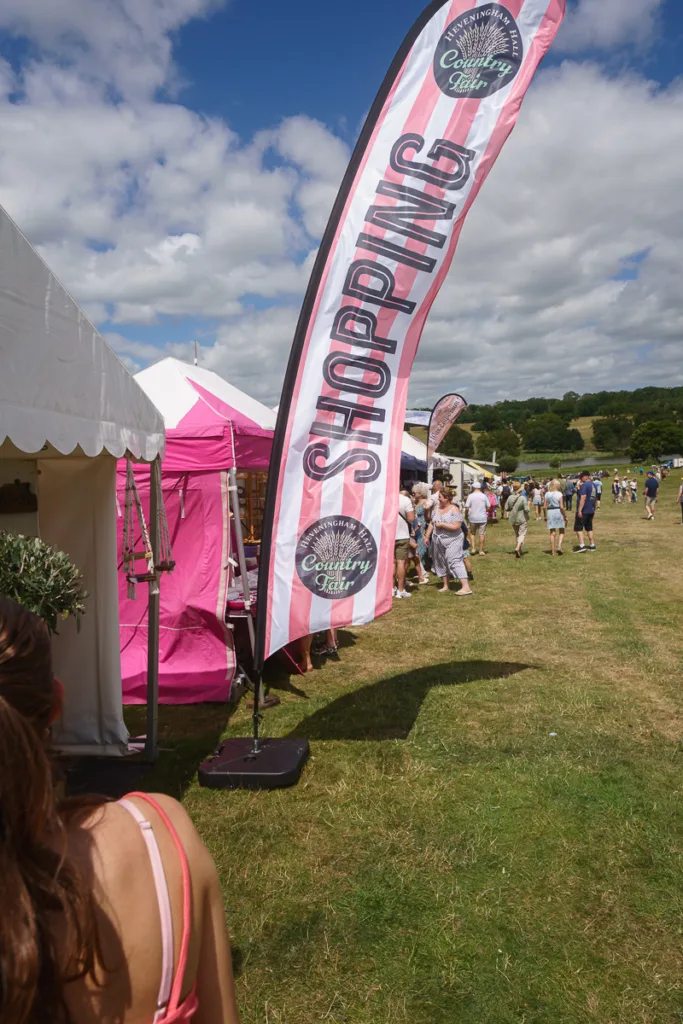 Shopping area at country fair with tents and flags.