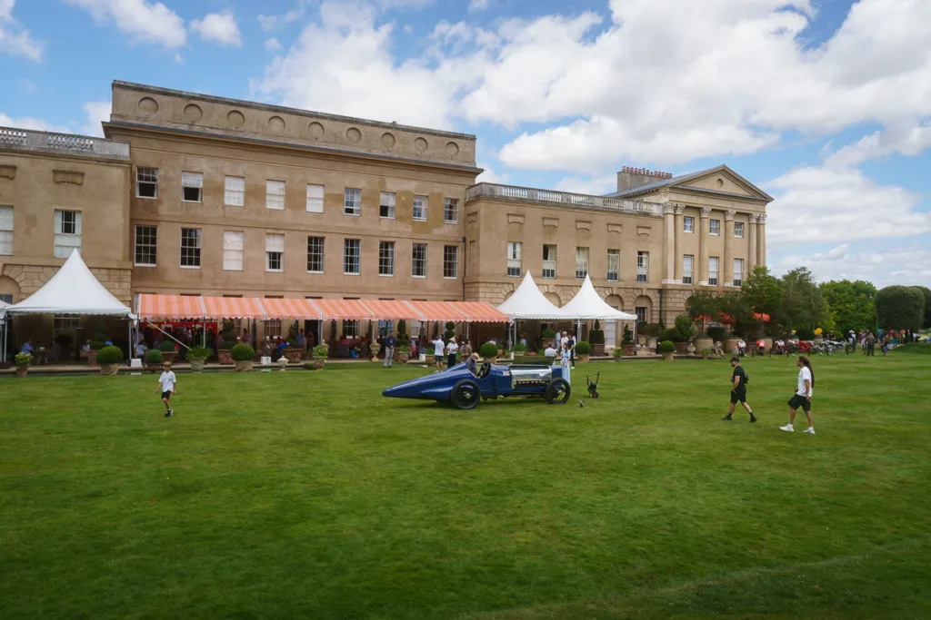 Historic mansion with lawn event and vintage car display.