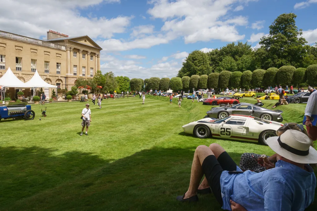 Classic car show on estate lawn, sunny day event.