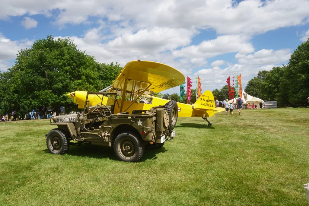 Yellow vintage aircraft and military jeep on grass