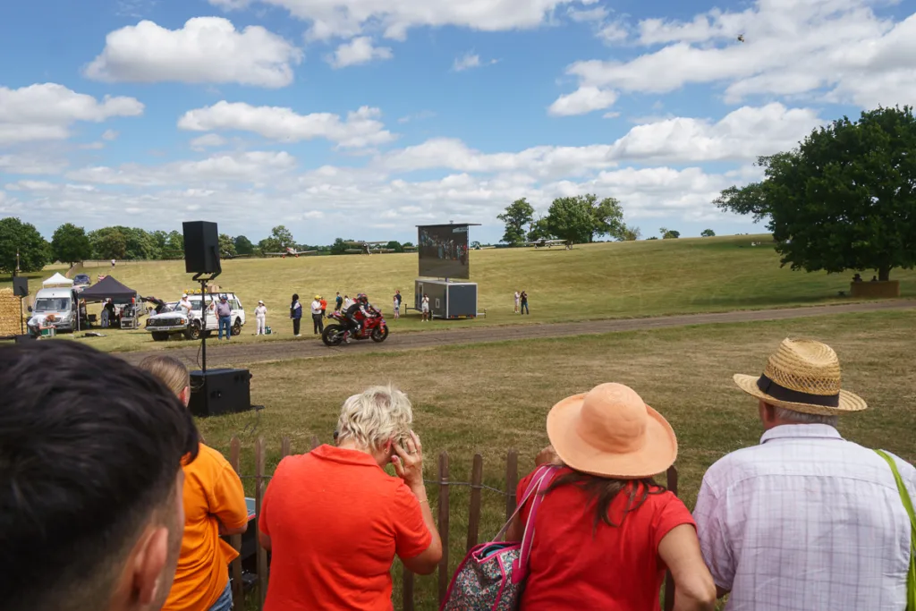 People watching motorcycle race in countryside.