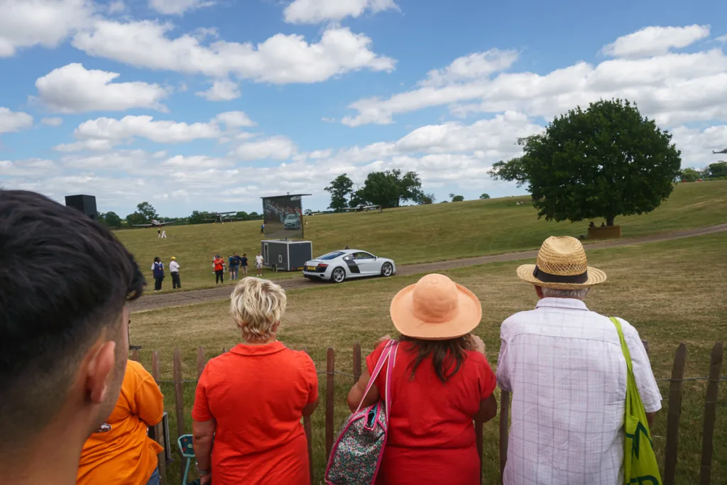 Spectators watching a car at outdoor event.