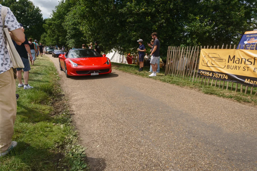 Red sports car on rural road scene.