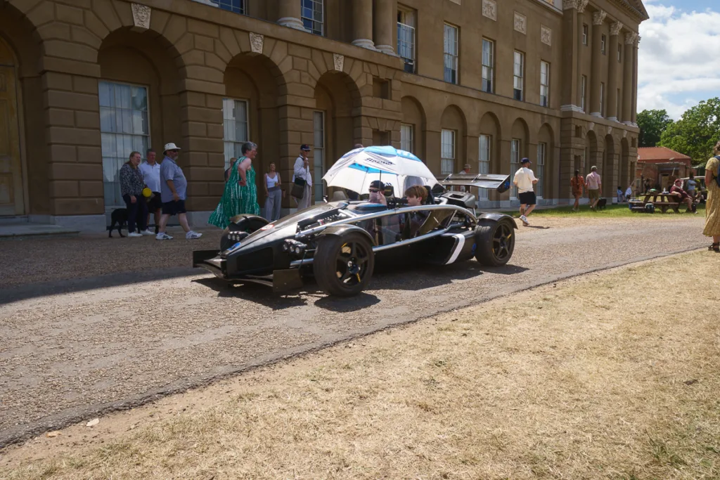 People near a sports car at historic building.