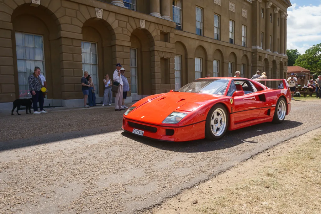 Classic red sports car in front of grand building.