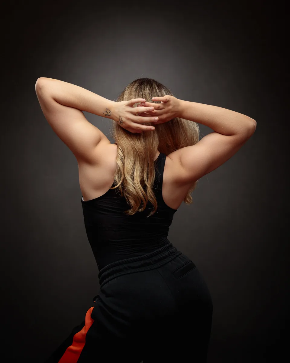 Woman posing with arms behind head in studio.