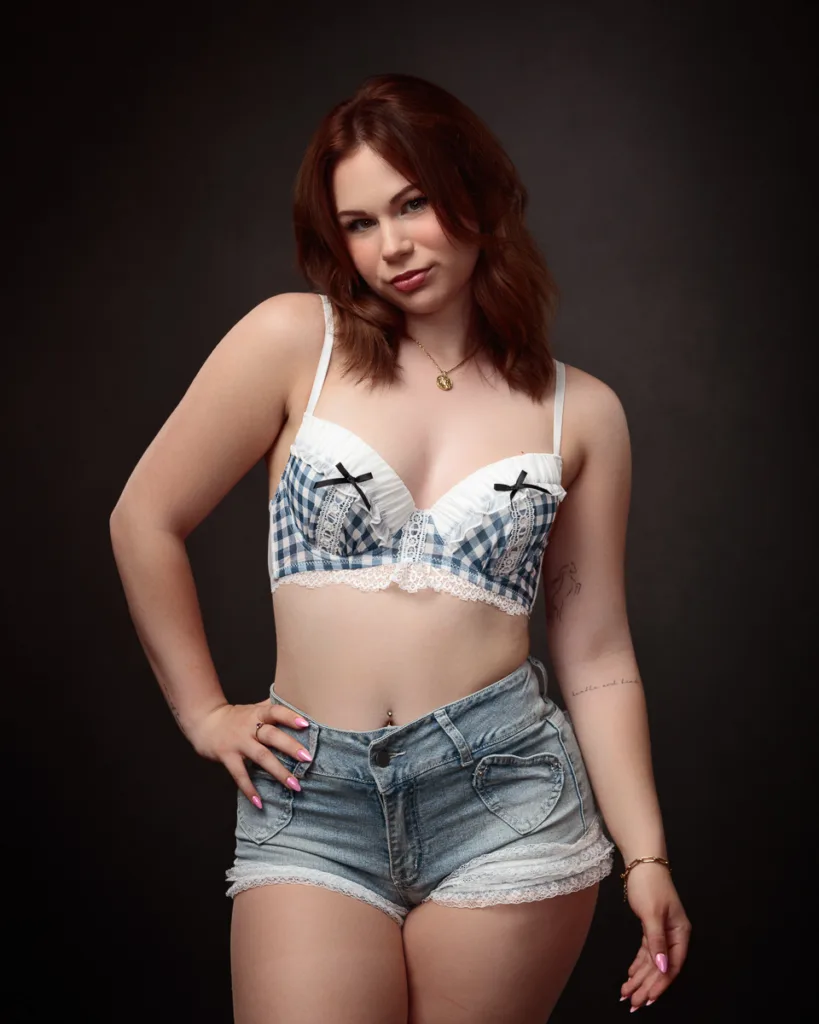 Woman in denim shorts and gingham top smiling.