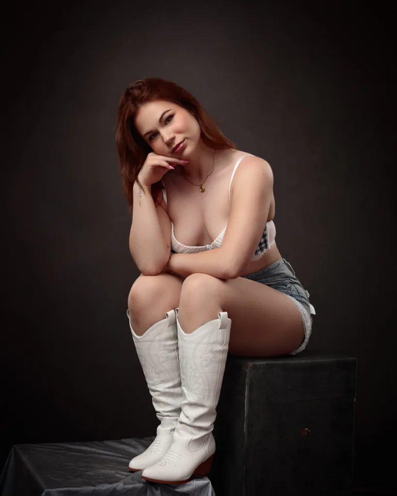 Woman in white boots posing on stool indoors