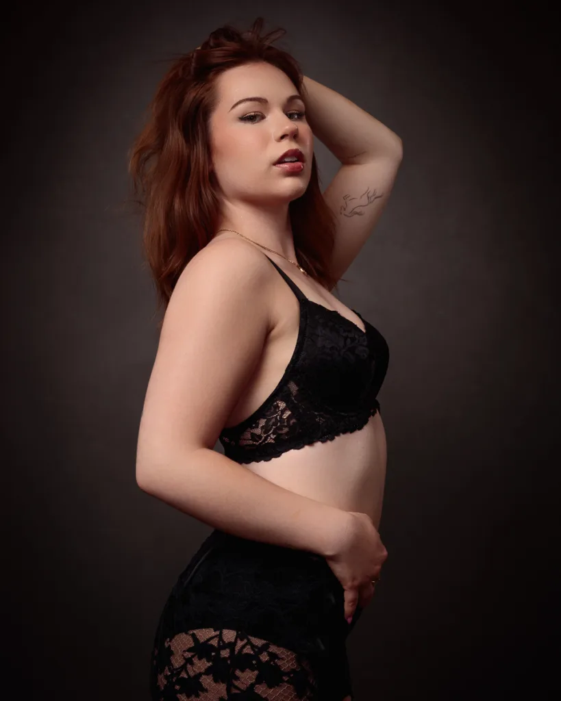 Person posing in black lace lingerie, side profile view.