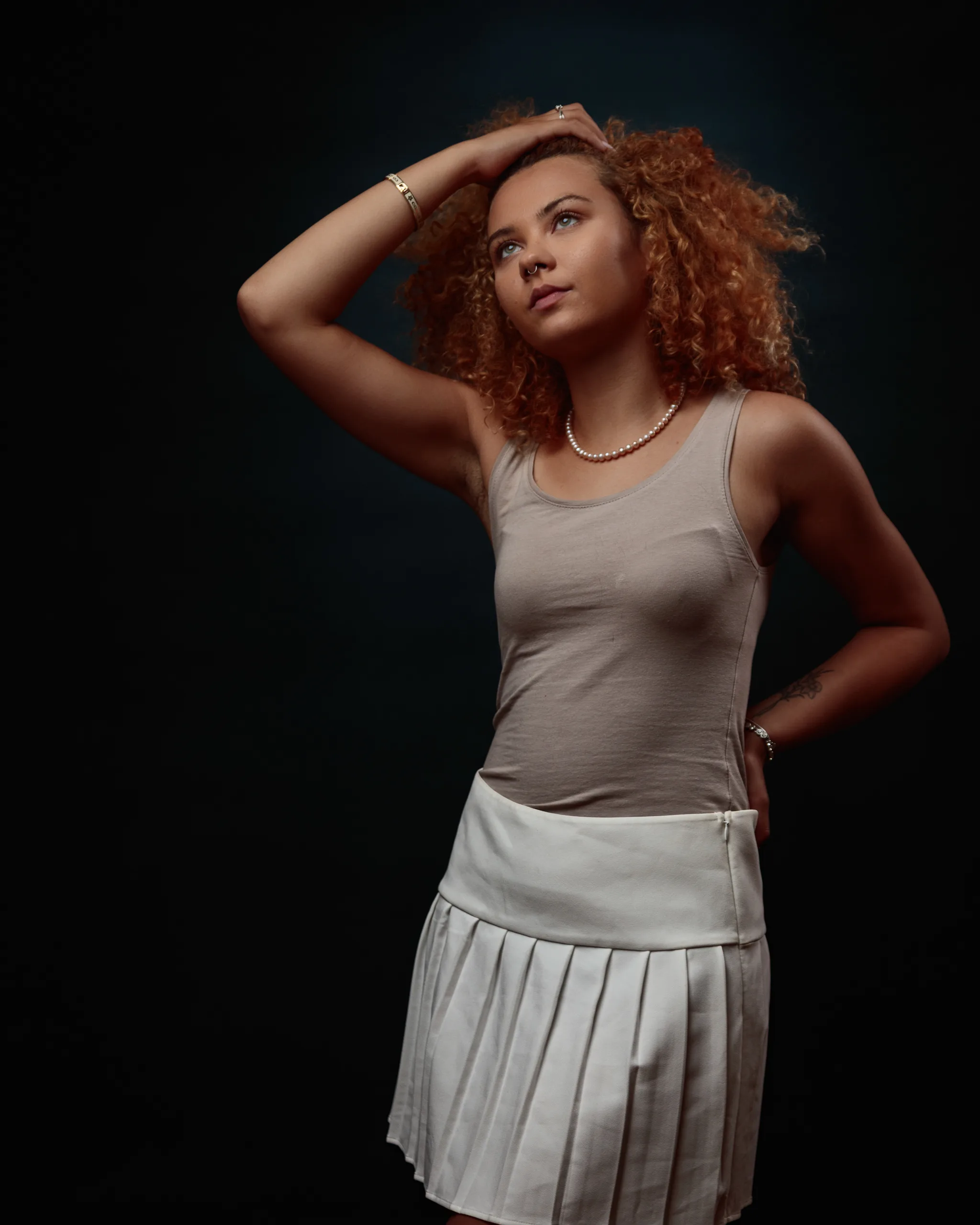 Woman with curly hair in thoughtful pose against dark background.