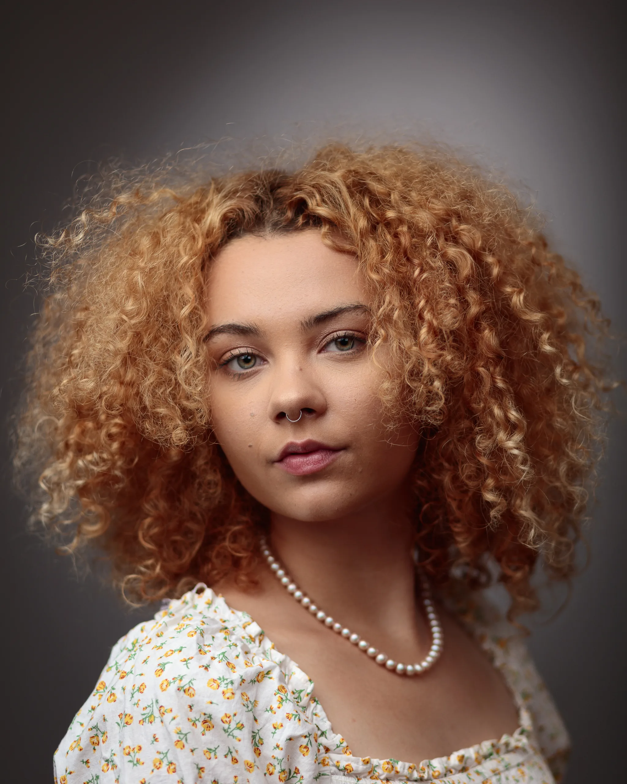 Woman with curly hair and pearl necklace.