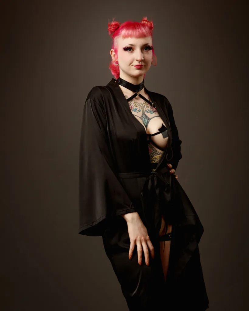 Person with pink hair in black outfit posing.
