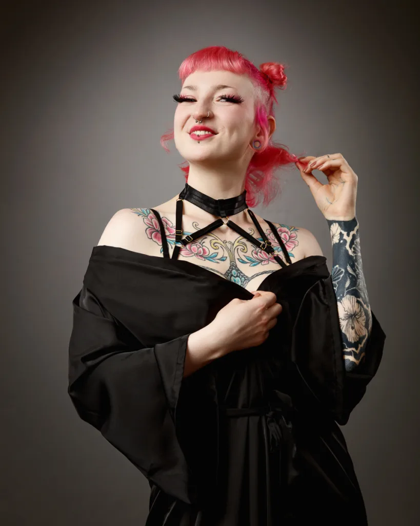 Woman with tattoos in black robe smiling.