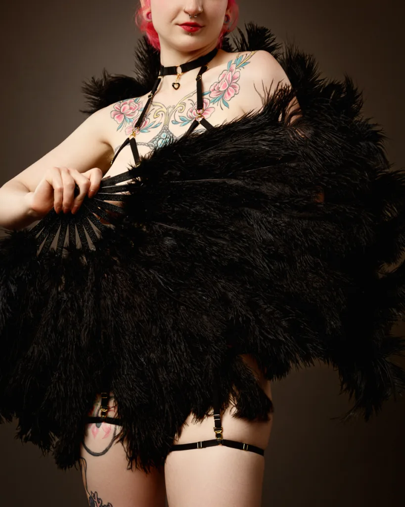Burlesque dancer with feather fans and tattoos.