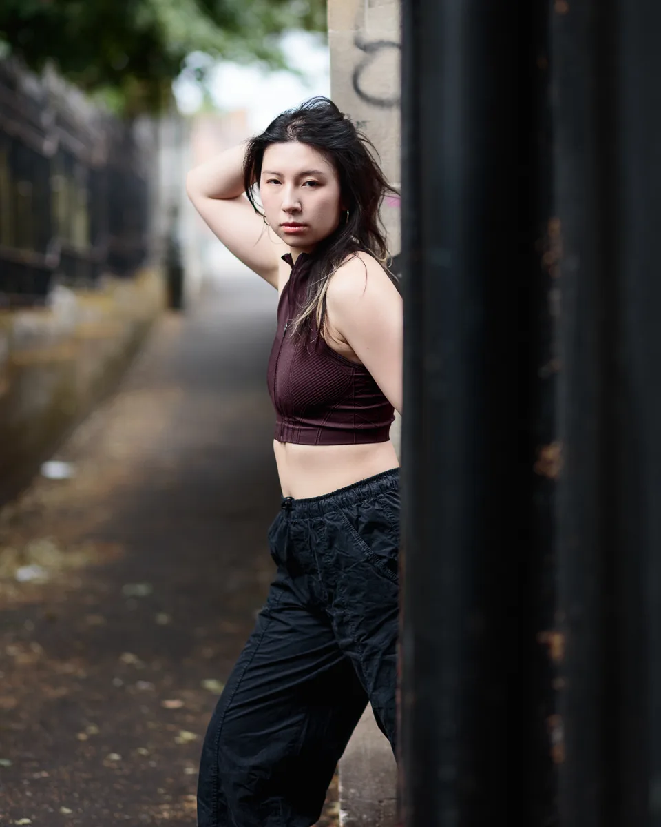 Person posing in casual urban alleyway setting.