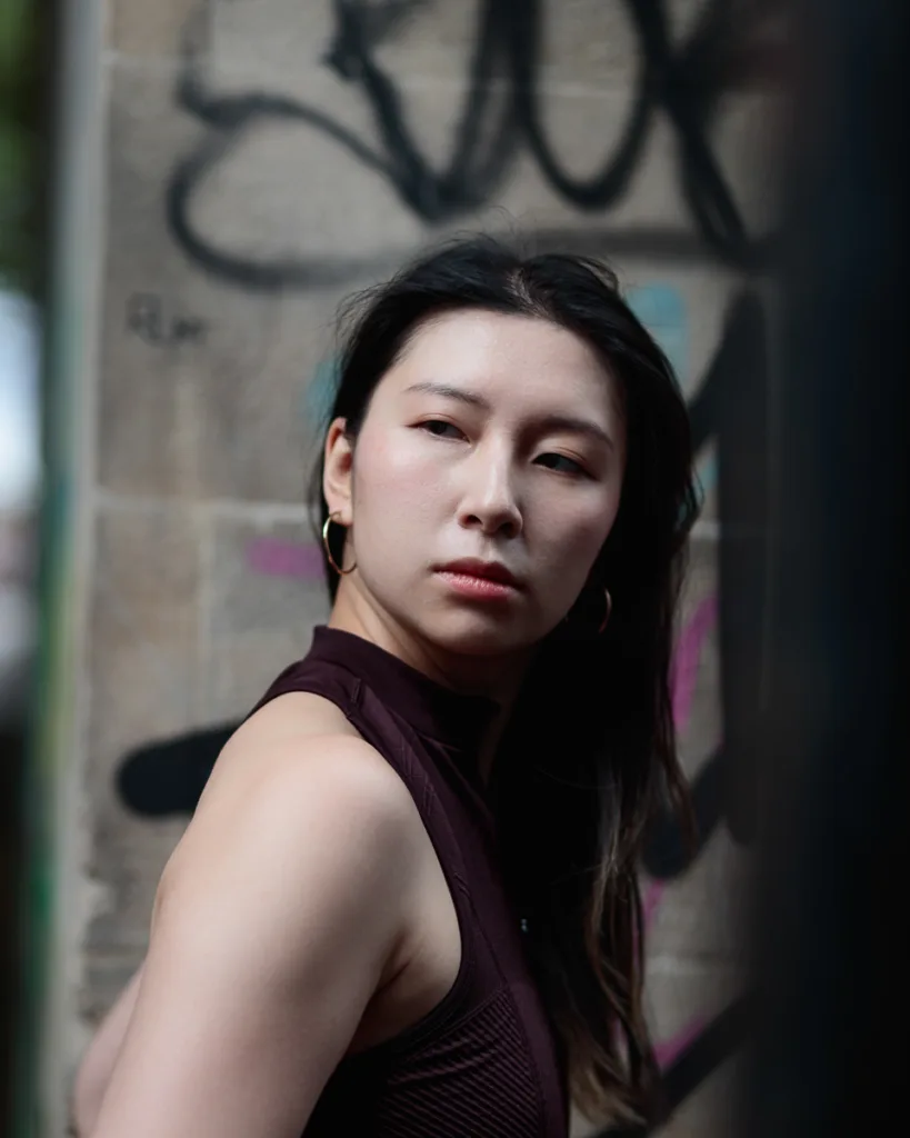 Person posing in front of graffiti-covered wall.