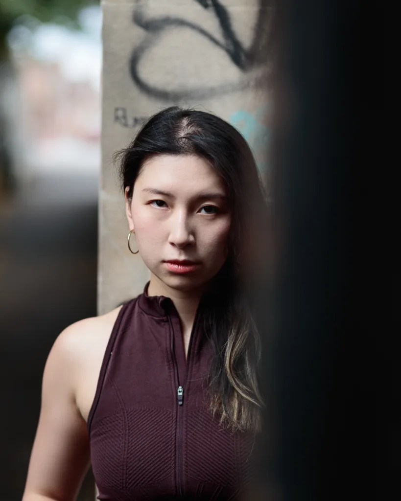 Woman in burgundy top near graffiti wall.