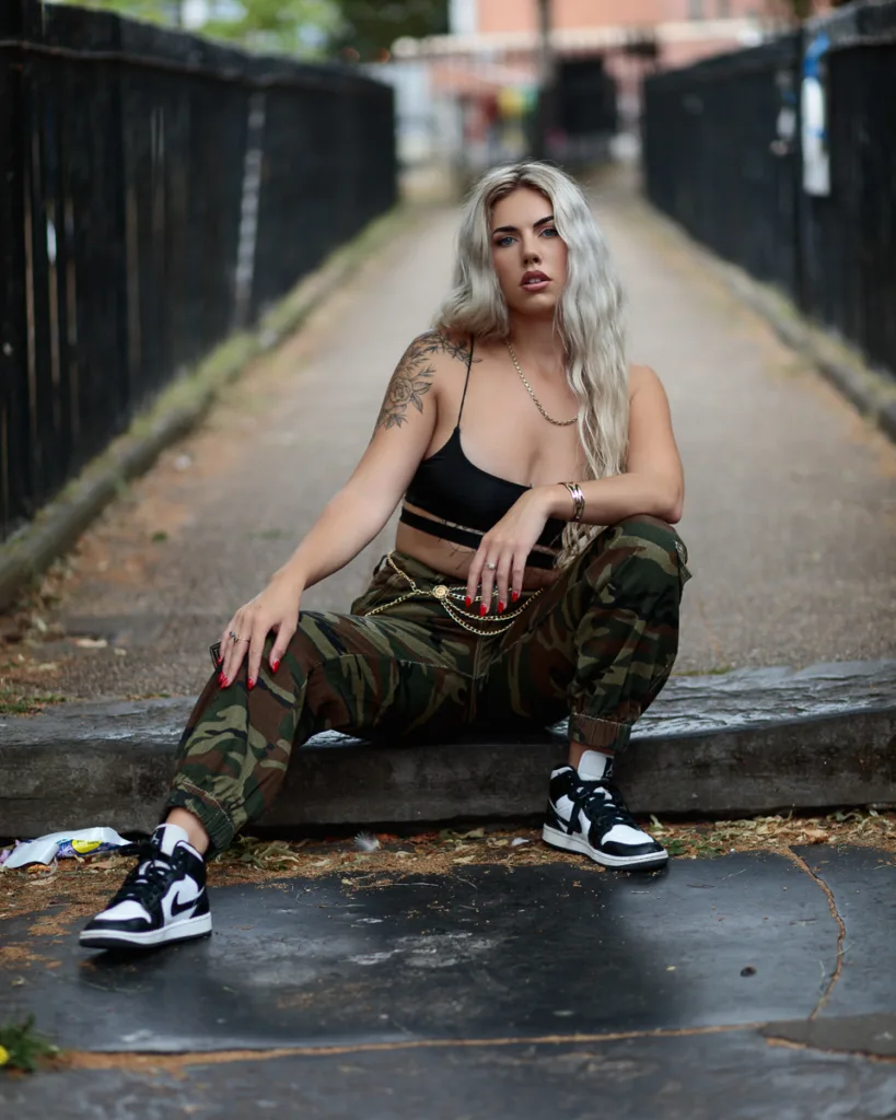 Woman in urban outfit sitting on a pathway.