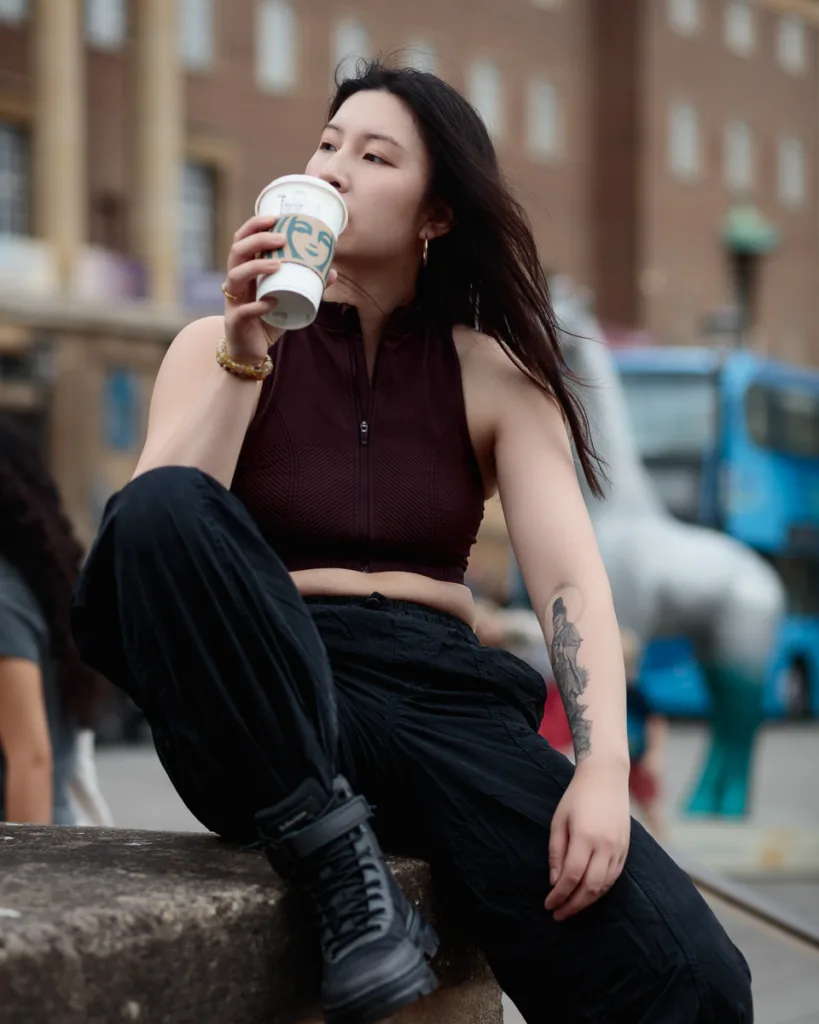 Person drinking coffee outdoors, city backdrop