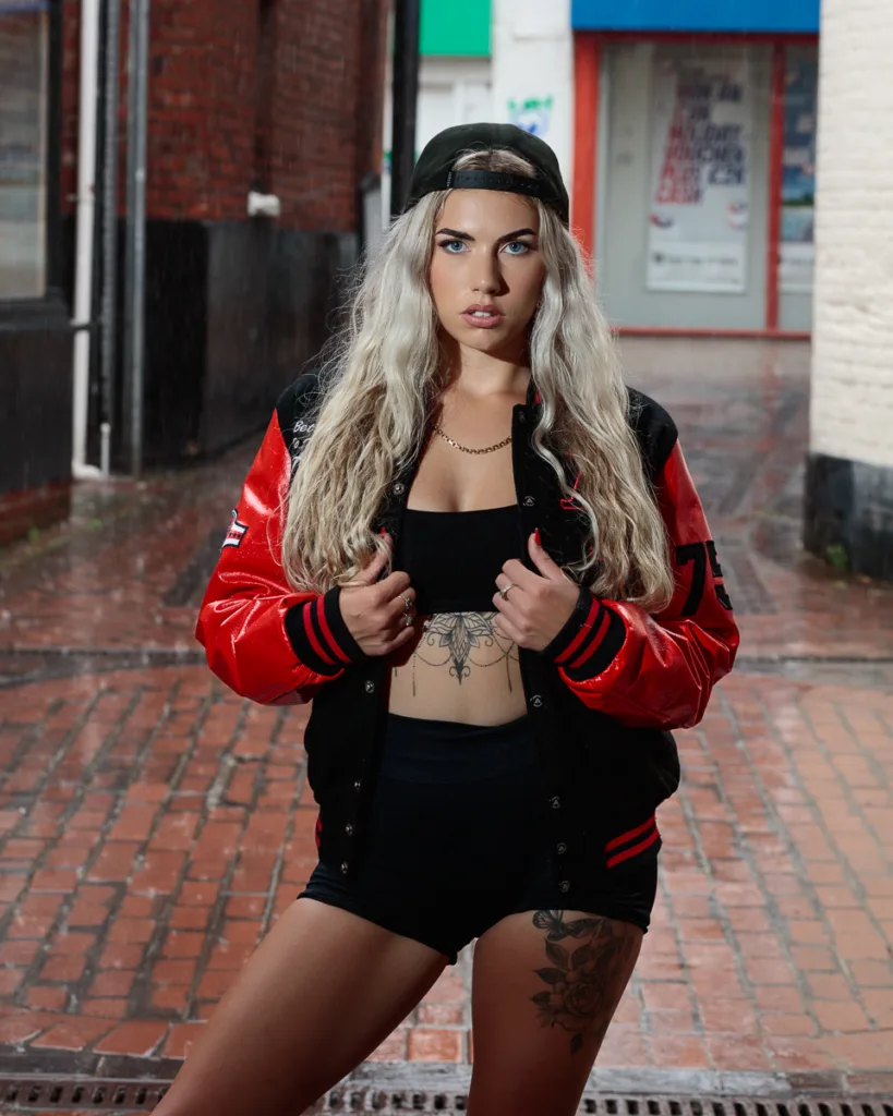 Woman in streetwear standing on rainy brick path.