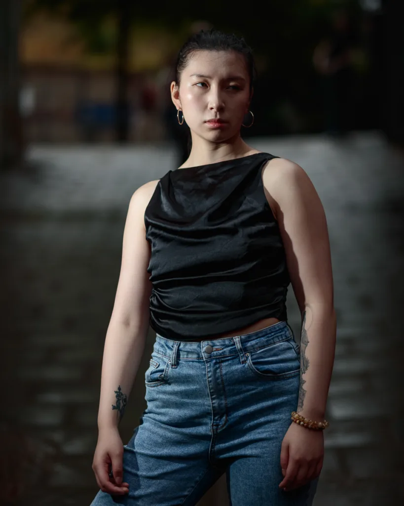 Person in black top and jeans standing outdoors.