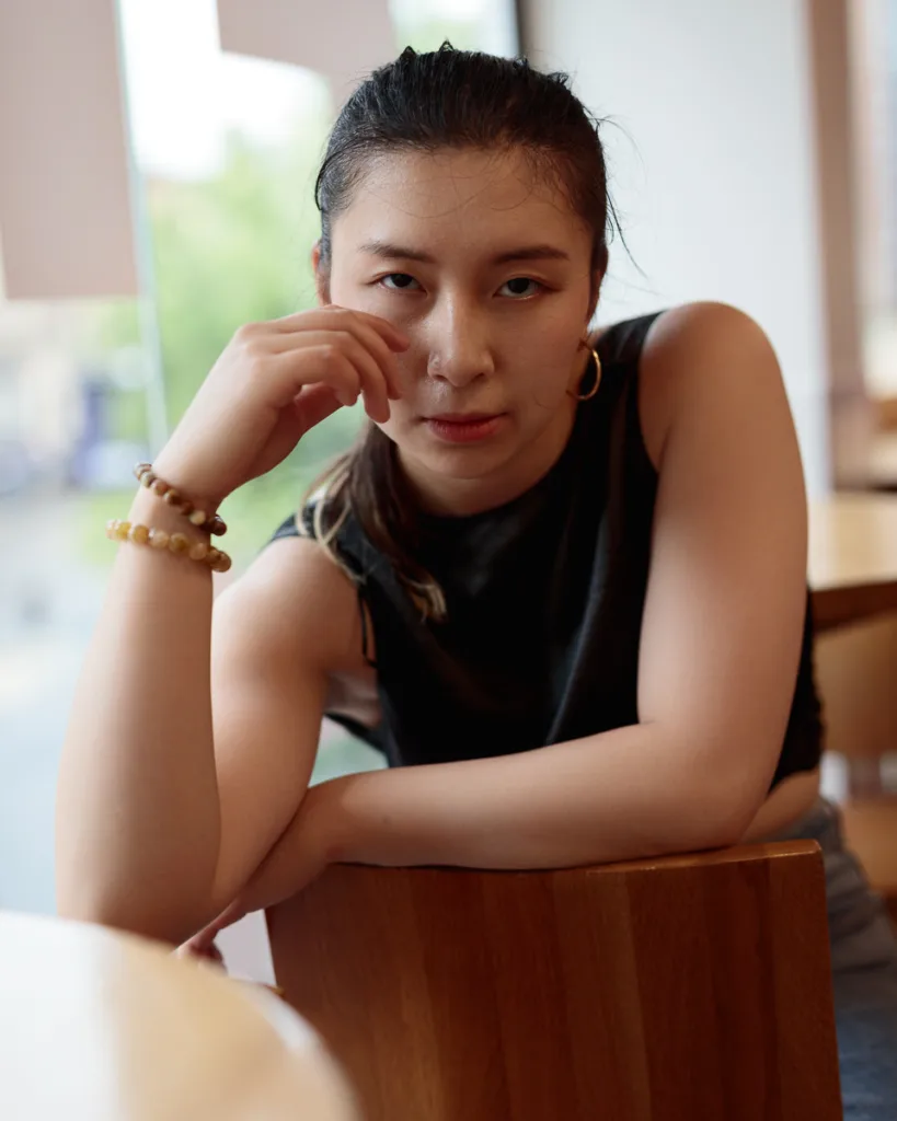 Person sitting on a wooden chair indoors.