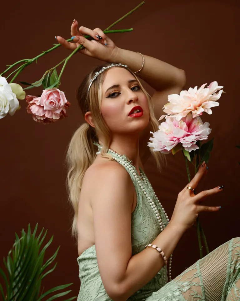 Woman in lace dress holding flowers, elegant pose.
