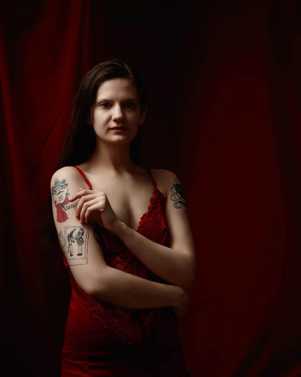 Woman in red dress with arm tattoos.