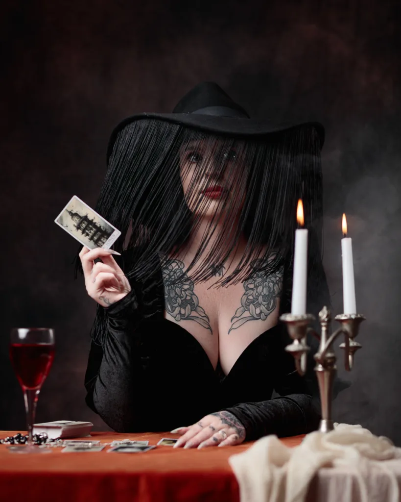 Woman with cards, candles, and gothic attire.