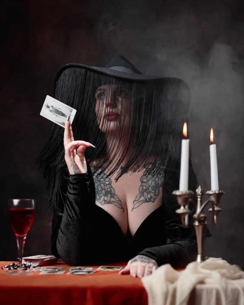 Woman in black hat holding tarot card indoors.