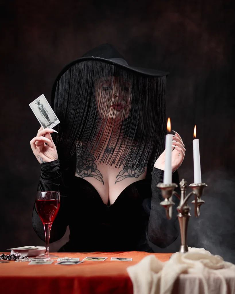 Woman holding tarot card with candles and wine.