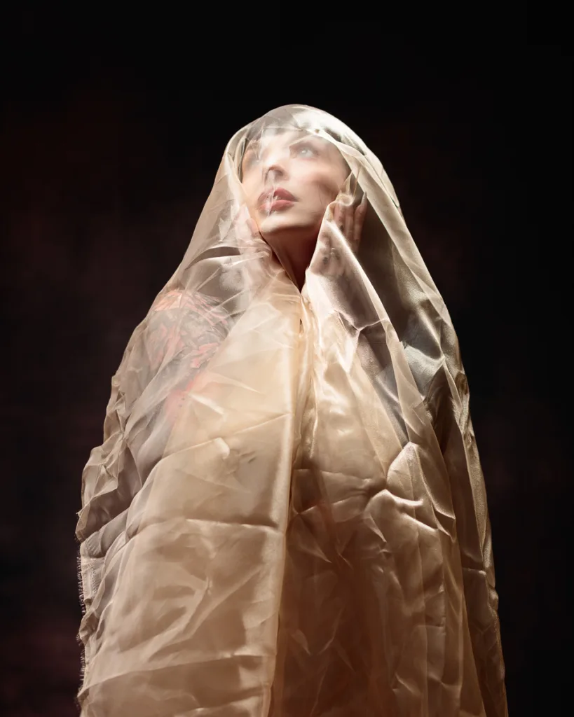 Person gazing upwards covered in sheer fabric.
