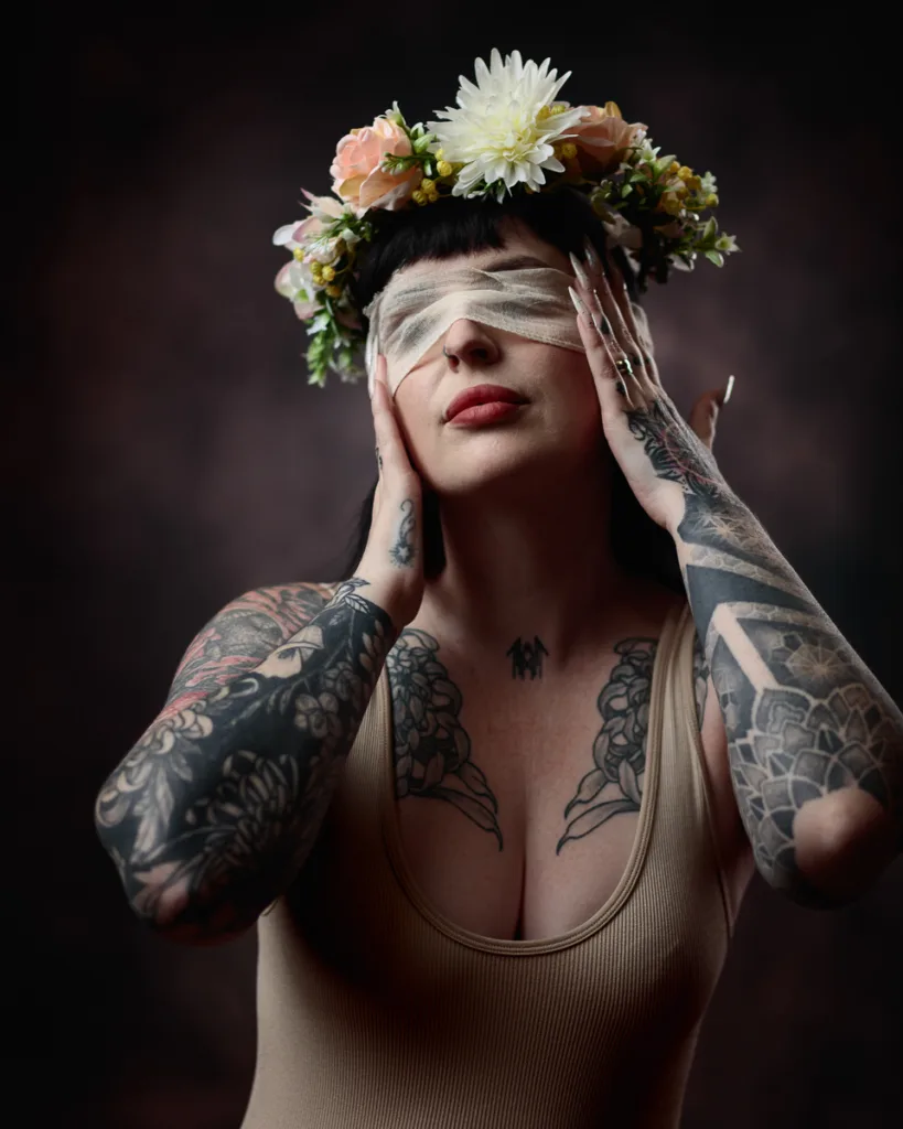Tattooed woman with flower crown and blindfold.