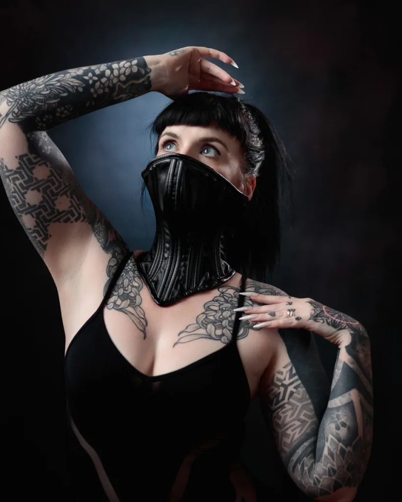 Tattooed person wearing black mask and dress