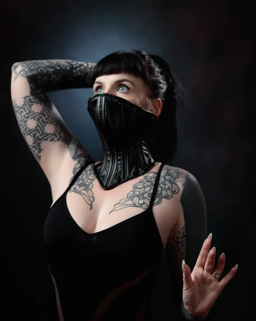 Tattooed woman in black corset fashion pose