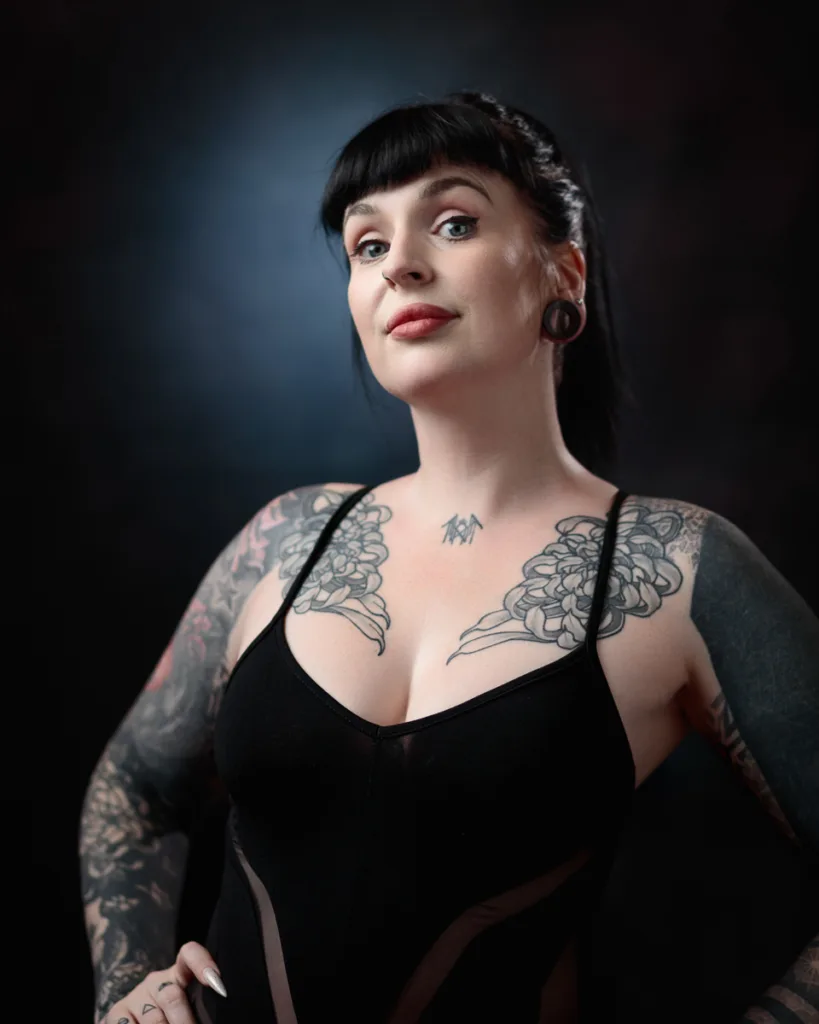 Person with tattoos in a black outfit posing.