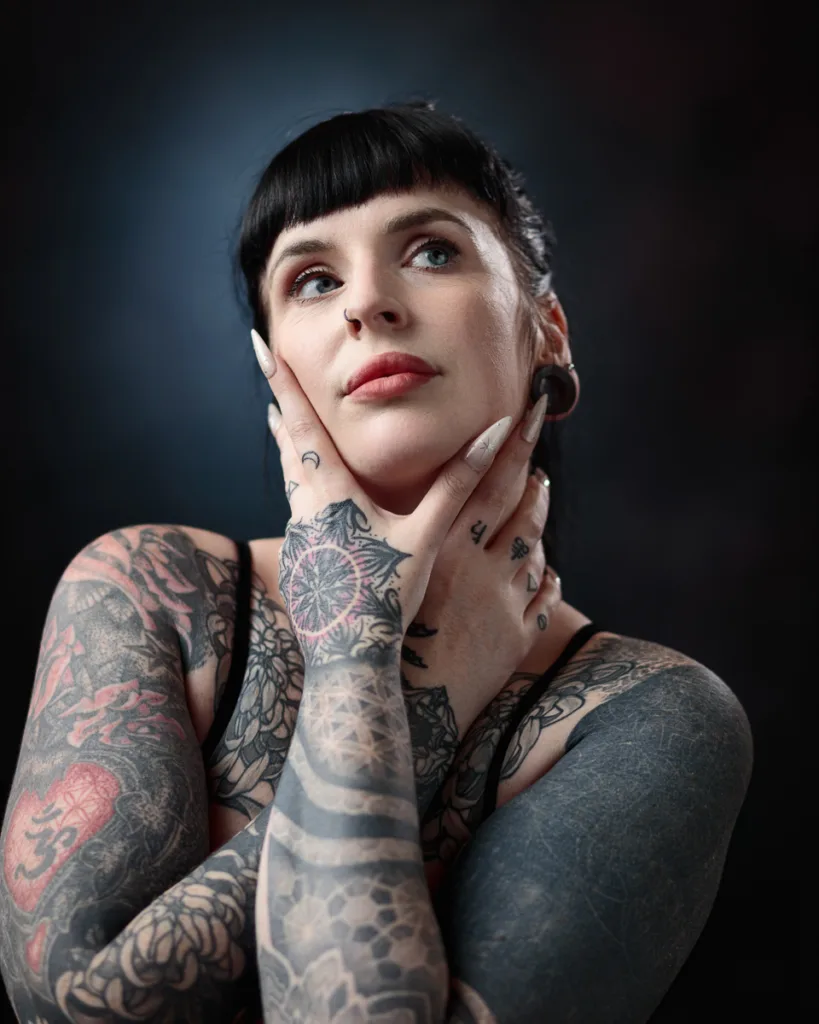 Tattooed woman posing with hands on face