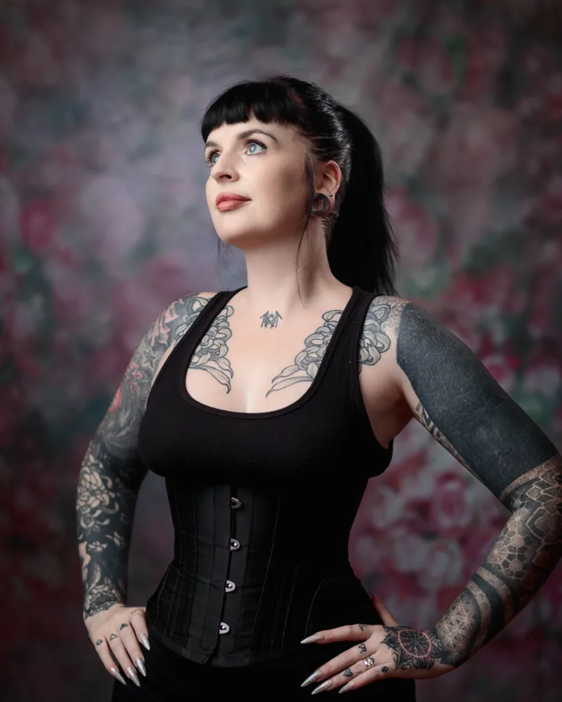 Tattooed woman in corset, looking upwards.